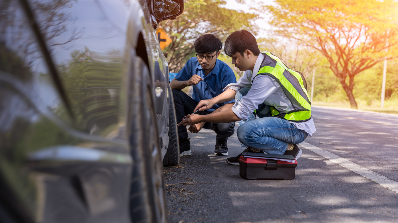 Emergency roadside assistance, technician helps with wheel replacement. Man changing wheel on a roadside. Roadside assistance